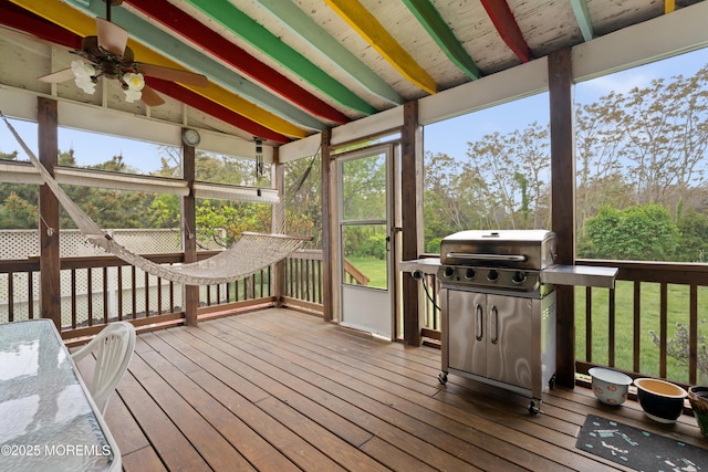 sunroom featuring a wealth of natural light, a ceiling fan, and beamed ceiling