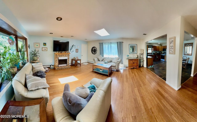 82 Bonita Rd, Waretown, NJ 08758 - living room featuring baseboards, light wood finished floors, a skylight, and a tile fireplace