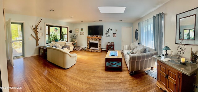 82 Bonita Rd, Waretown, NJ 08758 - living room with a skylight, a baseboard radiator, a fireplace with raised hearth, and wood finished floors