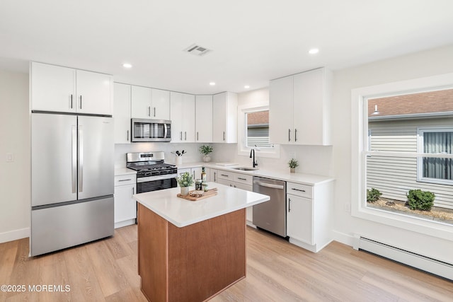 kitchen with visible vents, appliances with stainless steel finishes, baseboard heating, light countertops, and light wood-style flooring