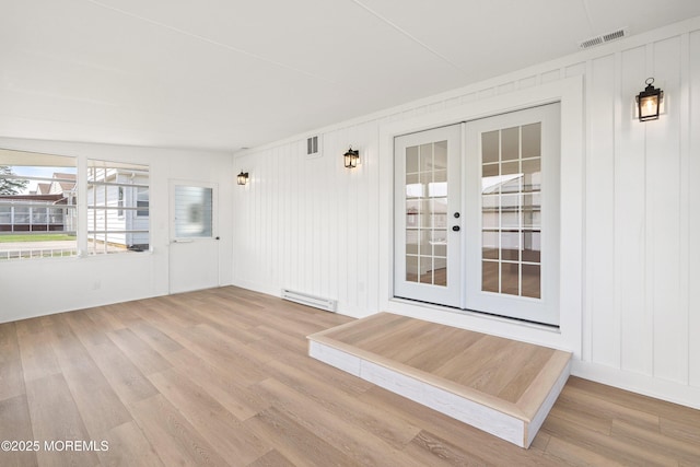 interior space with french doors, a baseboard heating unit, and visible vents