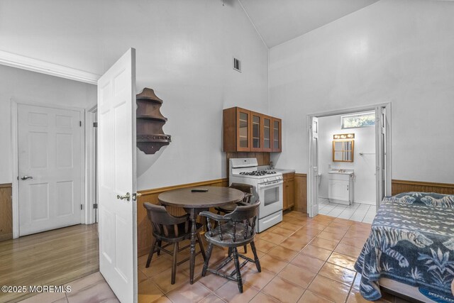 18 Schoolhouse Rd, Cream Ridge, NJ 08514 - kitchen featuring visible vents, glass insert cabinets, gas range gas stove, high vaulted ceiling, and a wainscoted wall
