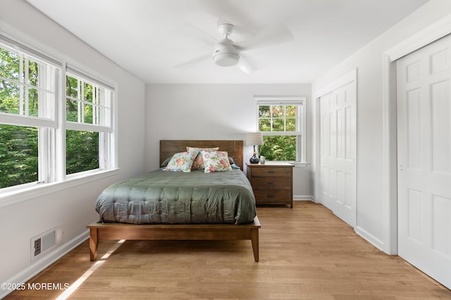 bedroom featuring baseboards, light wood-type flooring, and visible vents