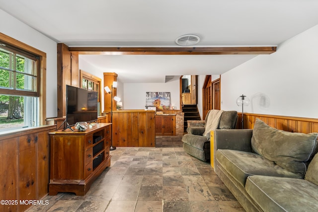 living area with wooden walls, a wainscoted wall, stairs, stone finish flooring, and visible vents