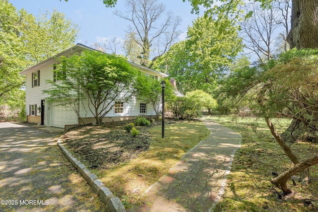 view of side of home featuring an attached garage and driveway