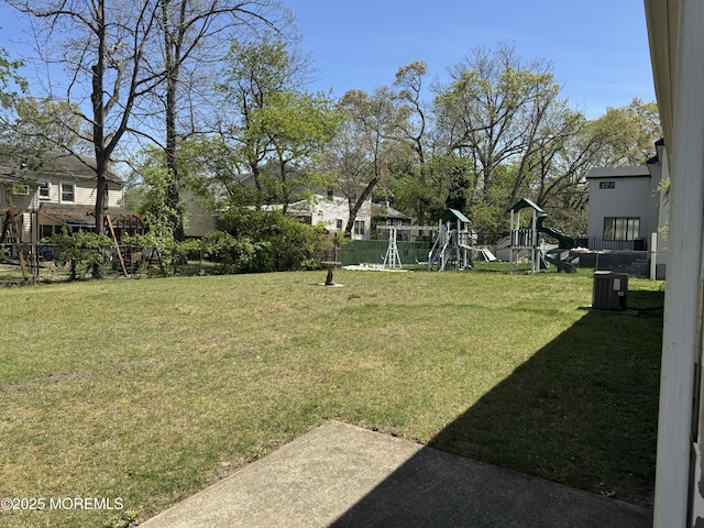 view of yard featuring central AC, a playground, and fence