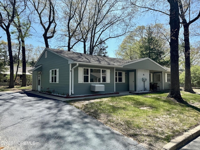 single story home with aphalt driveway and roof with shingles