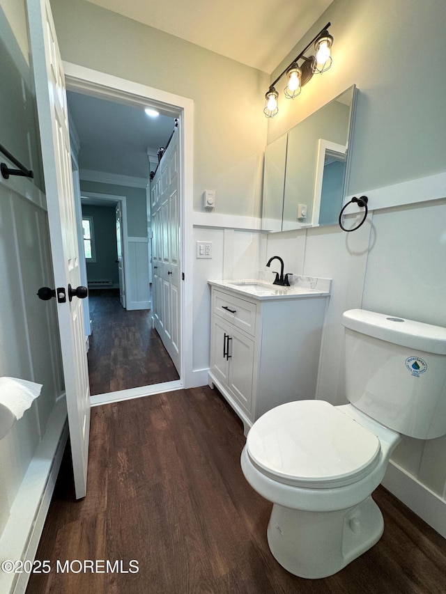 half bathroom with vanity, wainscoting, toilet, and wood finished floors
