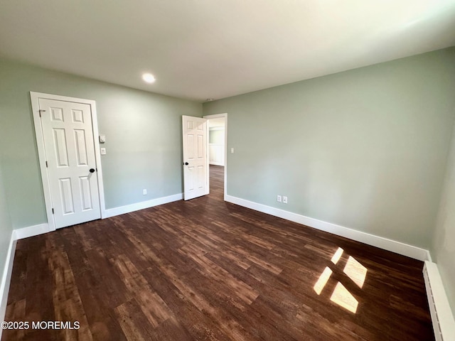 spare room featuring dark wood-style flooring, baseboards, recessed lighting, and baseboard heating