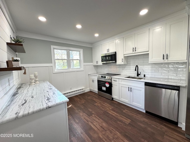 kitchen with crown molding, appliances with stainless steel finishes, baseboard heating, a sink, and white cabinetry