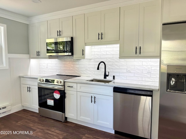 kitchen with light stone countertops, a sink, stainless steel appliances, decorative backsplash, and dark wood-type flooring
