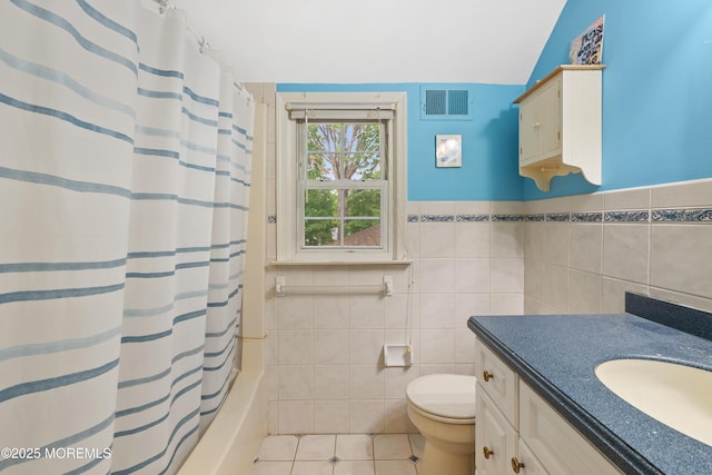 full bathroom featuring tile walls, vanity, toilet, tile patterned flooring, and shower / tub combo
