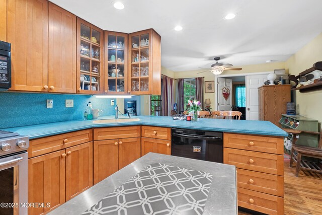 kitchen featuring black appliances, a peninsula, a sink, light wood-type flooring, and a ceiling fan