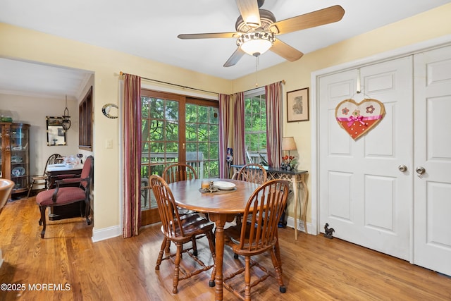 dining room featuring ceiling fan, light wood finished floors, and baseboards