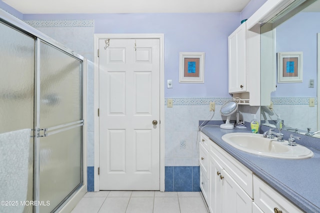 full bathroom featuring tile patterned flooring, wainscoting, a shower stall, vanity, and tile walls