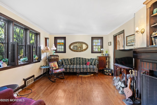 living area featuring wood finished floors, plenty of natural light, and crown molding