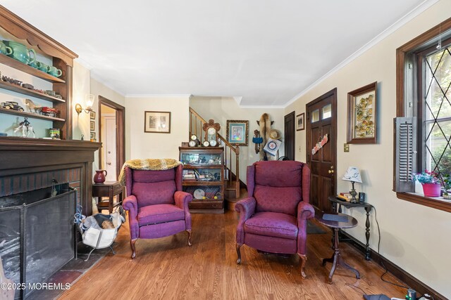 living area with wood finished floors, stairway, ornamental molding, and a brick fireplace
