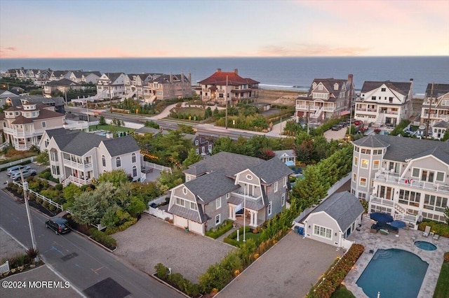 aerial view at dusk featuring a residential view and a water view