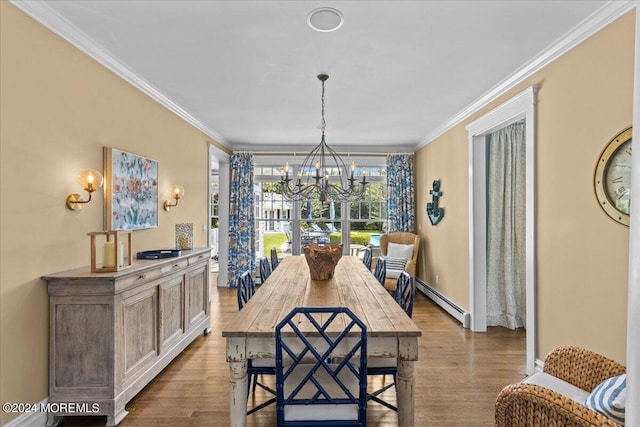 dining space with a notable chandelier, a baseboard heating unit, ornamental molding, and wood finished floors