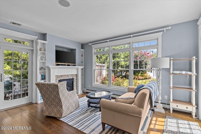 living room with visible vents, a baseboard heating unit, a glass covered fireplace, and wood finished floors