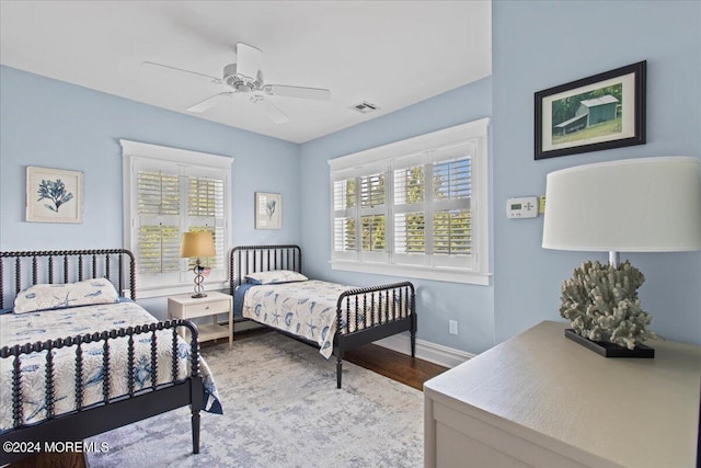 bedroom with visible vents, baseboards, wood finished floors, and multiple windows