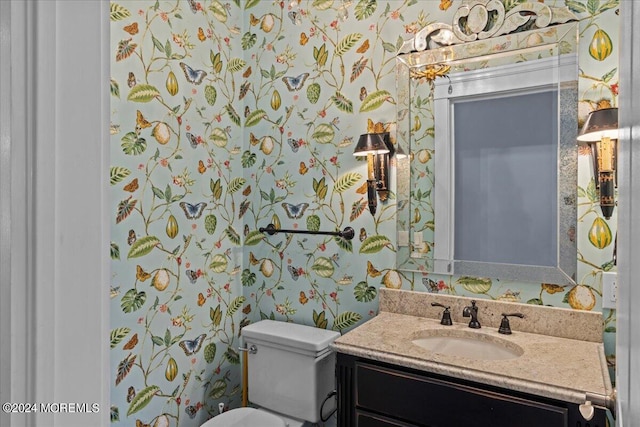 half bath with vanity, toilet, and wallpapered walls