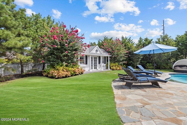 view of yard featuring fence, a fenced in pool, an outbuilding, a patio, and an exterior structure