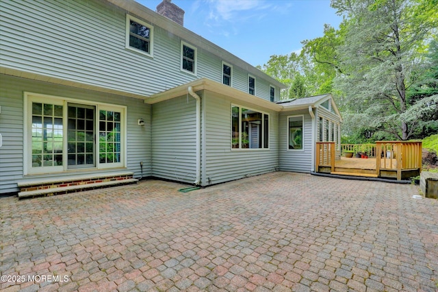9 Berkshire Ct, Holmdel, NJ 07733 - rear view of house with a deck, a patio area, and a chimney
