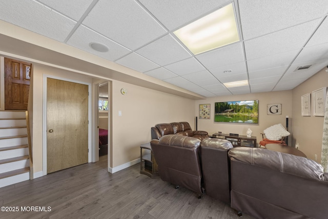 living area with a paneled ceiling, baseboards, wood finished floors, visible vents, and stairway