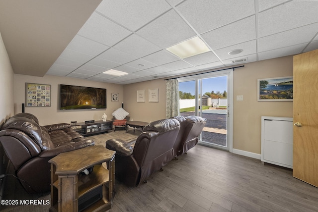living room featuring baseboards, a drop ceiling, wood finished floors, and visible vents