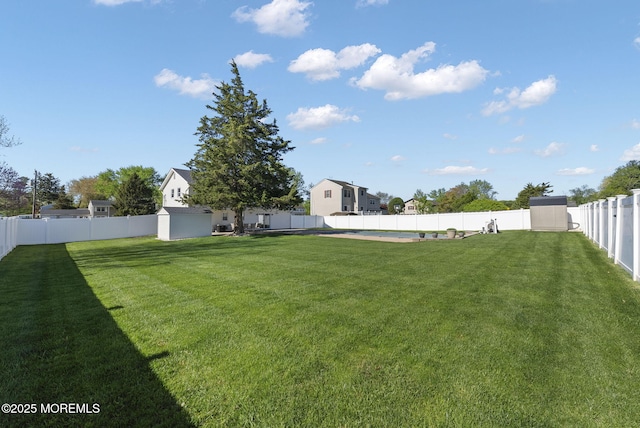view of yard featuring an outbuilding, a fenced backyard, and a storage unit