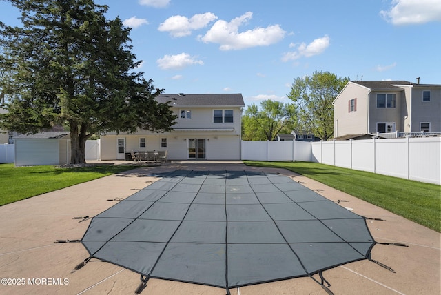 view of pool featuring fence, an outbuilding, a patio, and a lawn