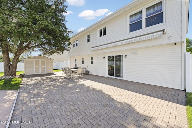 back of property with fence, a storage unit, a patio area, an outbuilding, and outdoor dining space