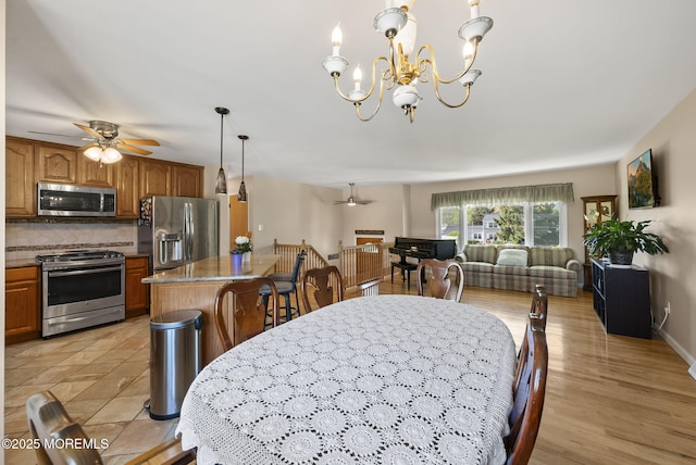 dining space with ceiling fan with notable chandelier