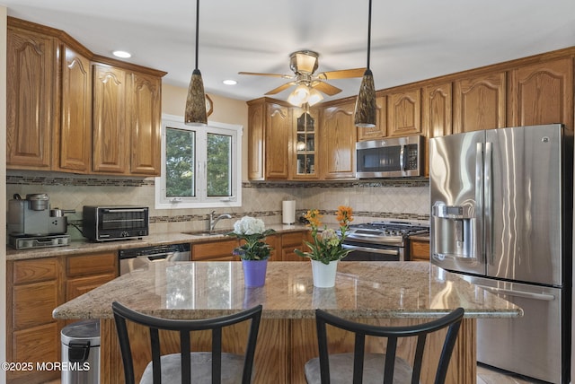 kitchen with light stone counters, brown cabinets, a kitchen bar, and stainless steel appliances