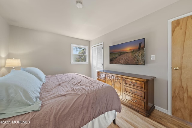bedroom with light wood-style floors, baseboards, and a closet