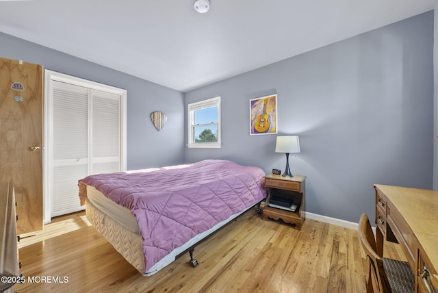 bedroom with baseboards, a closet, and light wood finished floors
