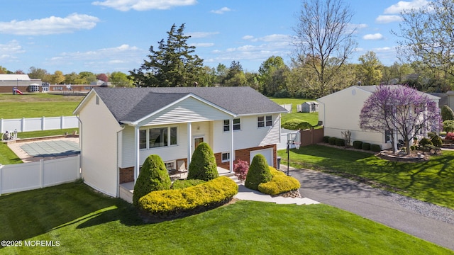 split foyer home featuring a garage, fence, driveway, and a front yard