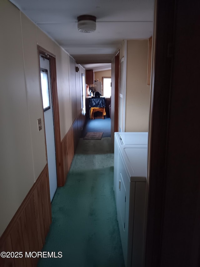 hall featuring light carpet, a decorative wall, and washer and clothes dryer