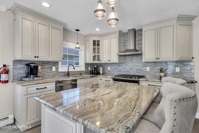 kitchen featuring wall chimney range hood, appliances with stainless steel finishes, a sink, baseboard heating, and light stone countertops