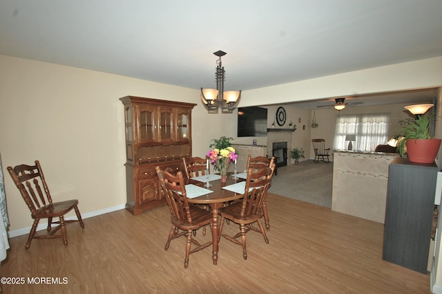 711 Edmunds Ave, Union Beach, NJ 07735 - dining room with light wood-style floors, baseboards, a glass covered fireplace, and ceiling fan with notable chandelier