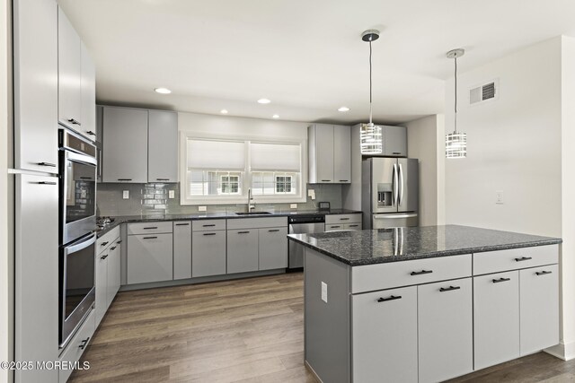 305 W 18th St, Ship Bottom, NJ 08008 - kitchen with appliances with stainless steel finishes, light wood finished floors, a sink, tasteful backsplash, and decorative light fixtures