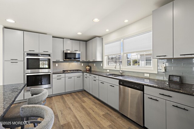 305 W 18th St, Ship Bottom, NJ 08008 - kitchen with stainless steel appliances, a sink, tasteful backsplash, light wood-style flooring, and dark stone countertops
