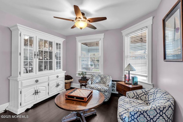 living area with baseboards, ceiling fan, and dark wood-style floors