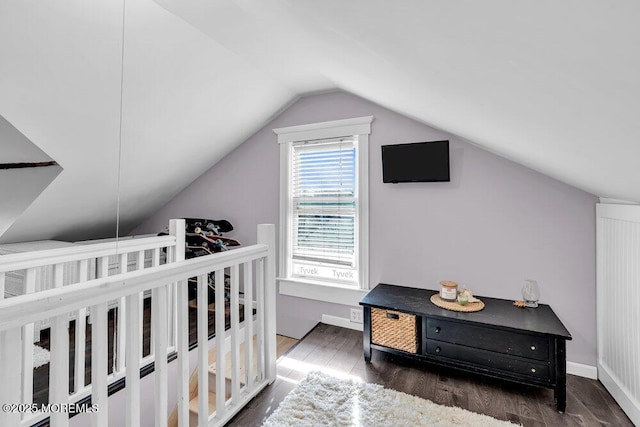 bedroom featuring baseboards, wood finished floors, and lofted ceiling