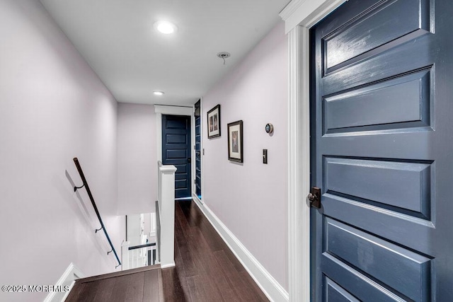 corridor with dark wood-type flooring, recessed lighting, baseboards, and an upstairs landing