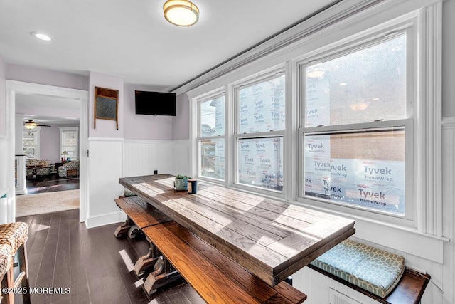 dining area with a ceiling fan, wainscoting, and dark wood-style floors