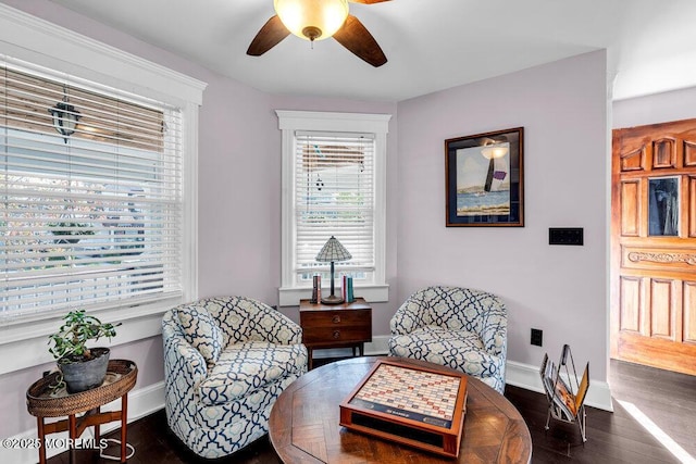 living area featuring dark wood-type flooring, a ceiling fan, and baseboards