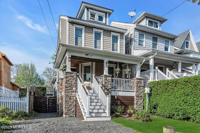 traditional style home featuring fence, covered porch, and stairway
