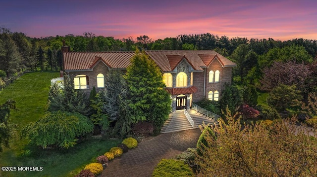 8 Tiberon Dr, Holmdel, NJ 07733 - view of front of house featuring stone siding, a forest view, a tile roof, and a chimney